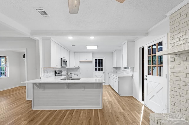 kitchen featuring decorative backsplash, white cabinets, and kitchen peninsula