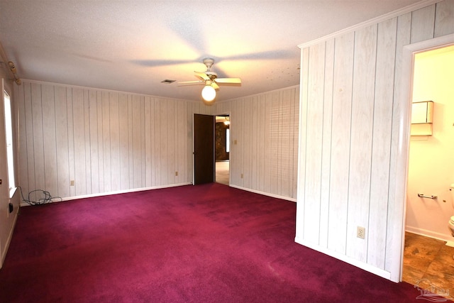 spare room featuring ornamental molding, dark colored carpet, and ceiling fan