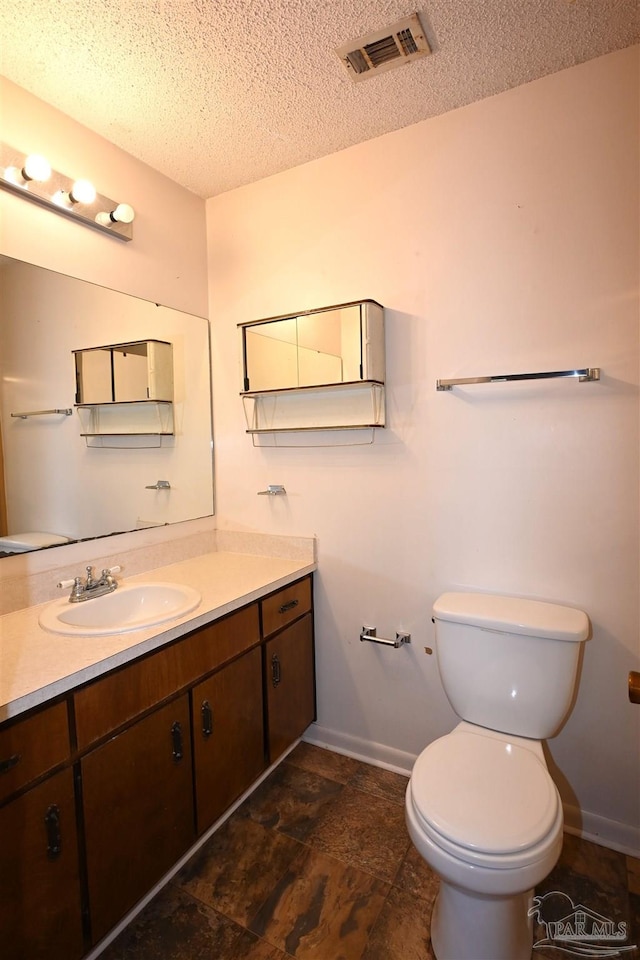 bathroom with toilet, vanity, and a textured ceiling