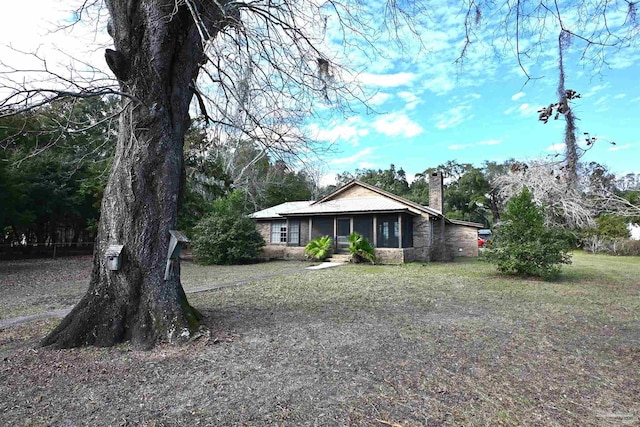 ranch-style home featuring a sunroom and a front lawn