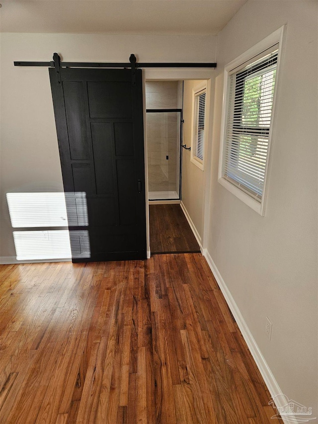 unfurnished bedroom featuring a barn door and wood-type flooring