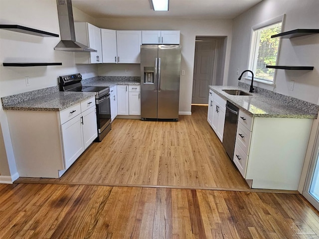 kitchen with white cabinetry, sink, stainless steel appliances, wall chimney range hood, and light wood-type flooring