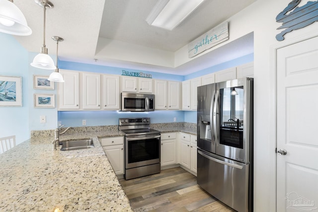 kitchen featuring sink, decorative light fixtures, appliances with stainless steel finishes, light stone countertops, and white cabinets