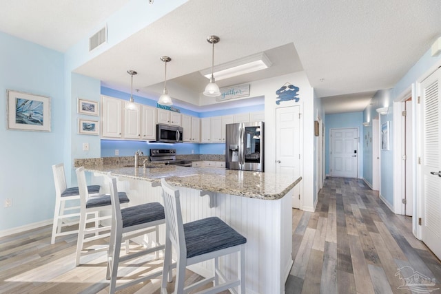 kitchen featuring hanging light fixtures, appliances with stainless steel finishes, a textured ceiling, and kitchen peninsula