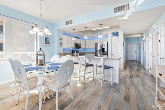 dining area with light hardwood / wood-style flooring and a notable chandelier