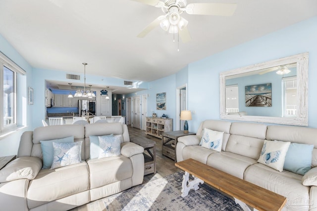 living room with wood-type flooring and ceiling fan with notable chandelier