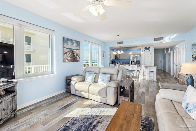 living room with hardwood / wood-style flooring and ceiling fan with notable chandelier