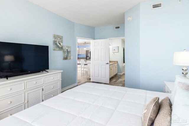 bedroom featuring ensuite bathroom, stainless steel fridge with ice dispenser, and hardwood / wood-style floors