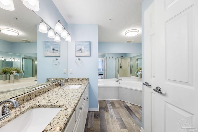 bathroom featuring wood-type flooring, plus walk in shower, a textured ceiling, and vanity