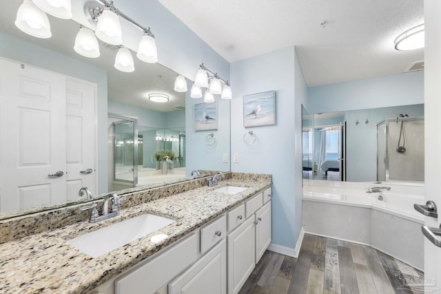 bathroom featuring vanity, plus walk in shower, hardwood / wood-style floors, and a textured ceiling