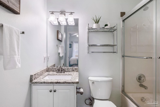 full bathroom featuring vanity, shower / bath combination with glass door, and toilet