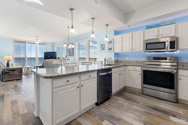 kitchen with sink, appliances with stainless steel finishes, white cabinets, decorative light fixtures, and kitchen peninsula