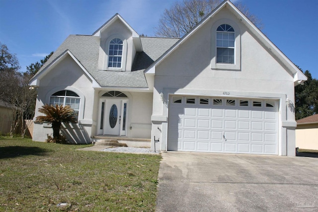 view of front of property with driveway, roof with shingles, a front yard, and stucco siding