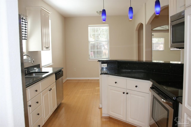 kitchen featuring appliances with stainless steel finishes, dark countertops, white cabinetry, and a sink