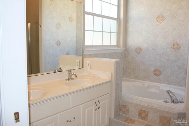 bathroom with double vanity, tiled bath, and a sink