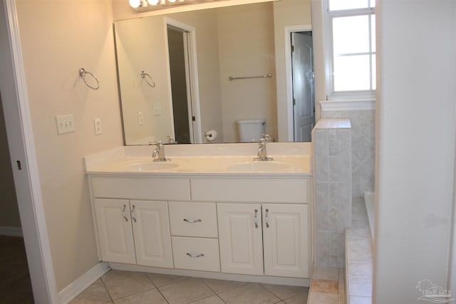 bathroom with toilet, tile patterned flooring, double vanity, and a sink