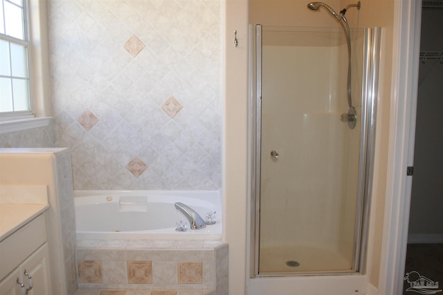 bathroom with a stall shower, a spacious closet, a bath, and vanity