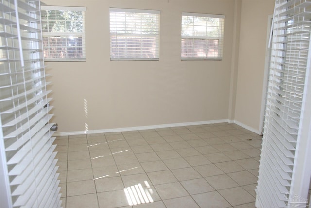 spare room with light tile patterned floors, plenty of natural light, and baseboards