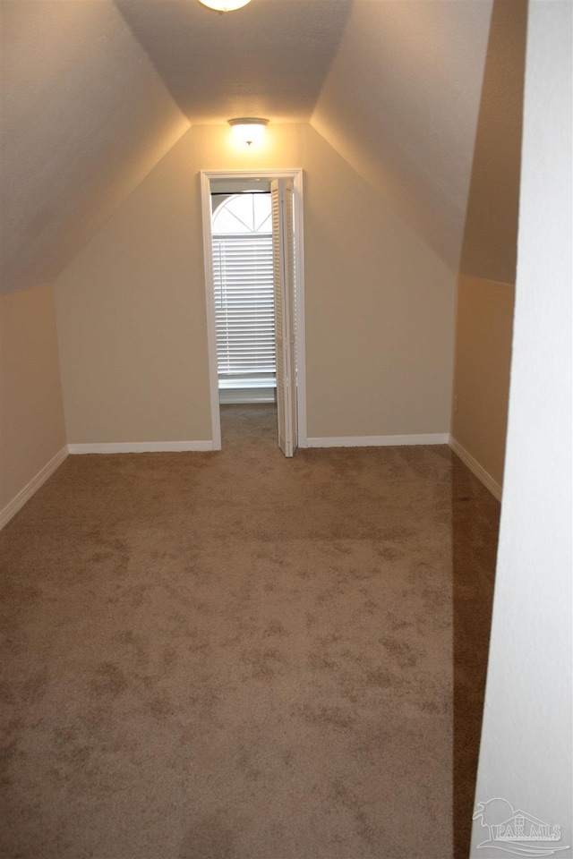 additional living space with vaulted ceiling, carpet flooring, and baseboards