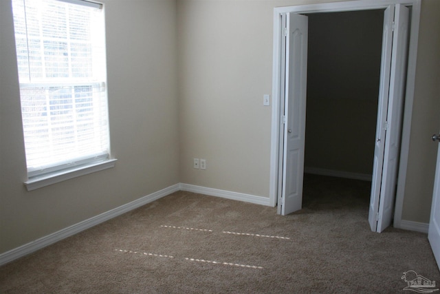 spare room featuring carpet and baseboards