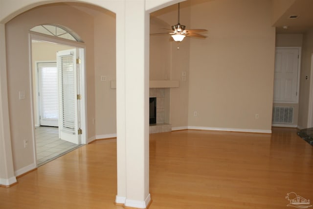 unfurnished living room featuring ceiling fan, a fireplace, visible vents, and wood finished floors