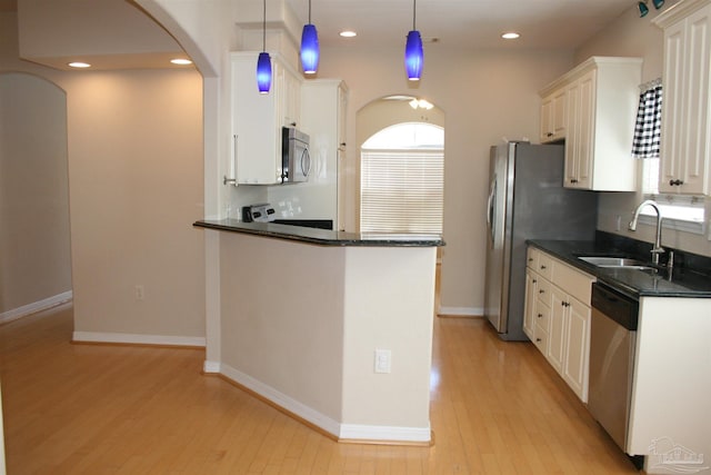 kitchen with a sink, white cabinetry, baseboards, appliances with stainless steel finishes, and light wood-type flooring