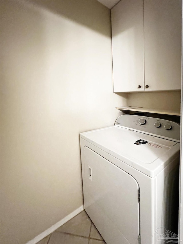 clothes washing area featuring washer / clothes dryer, light tile patterned floors, and cabinets