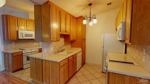 kitchen with light tile patterned flooring, sink, decorative light fixtures, a chandelier, and white appliances