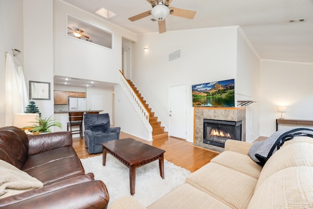 living room with a fireplace, ceiling fan, light hardwood / wood-style flooring, and high vaulted ceiling