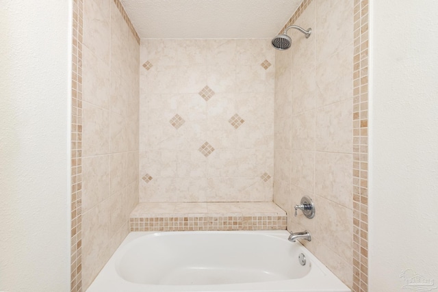 bathroom with tiled shower / bath combo and a textured ceiling