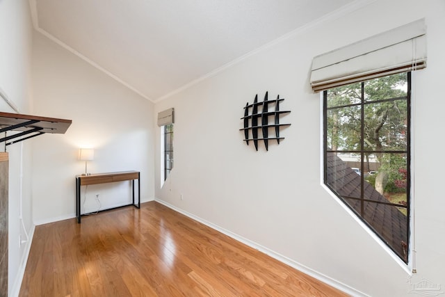 empty room featuring ornamental molding, vaulted ceiling, and hardwood / wood-style flooring