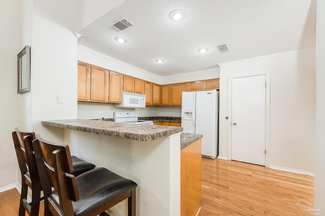 kitchen with light wood-type flooring, white appliances, a textured ceiling, and ornamental molding