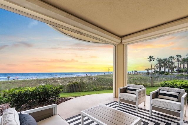 patio terrace at dusk featuring outdoor lounge area, fence, and a water view