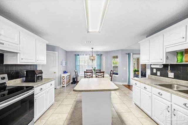 7951 Amethyst Dr, Pensacola, FL 32506 - kitchen featuring stainless steel range with electric stovetop, under cabinet range hood, light countertops, and decorative backsplash