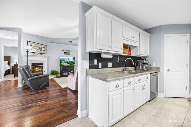 7951 Amethyst Dr, Pensacola, FL 32506 - kitchen featuring dishwasher, white cabinets, a sink, open floor plan, and a fireplace