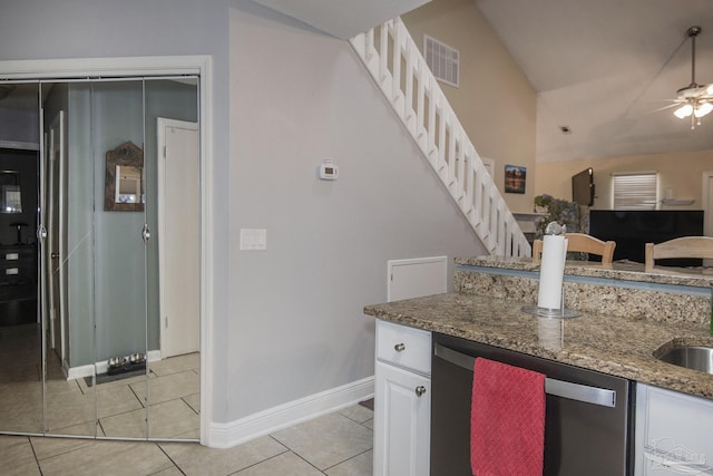 kitchen with ceiling fan, dark stone countertops, white cabinets, light tile patterned flooring, and stainless steel dishwasher