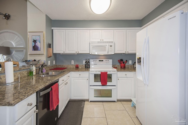 kitchen with white cabinetry, sink, dark stone countertops, light tile patterned floors, and white appliances