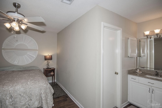 bedroom featuring dark hardwood / wood-style flooring, sink, a textured ceiling, and ceiling fan