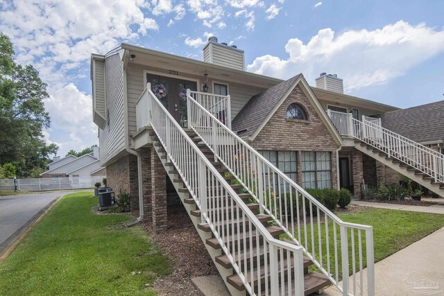 view of front of house with central AC and a front lawn