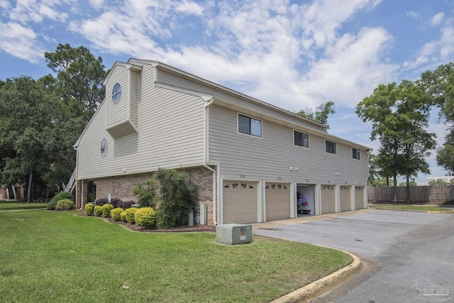 view of side of property featuring a garage and a lawn