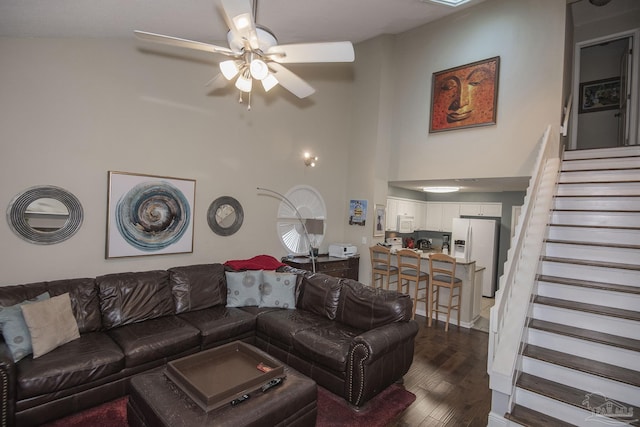 living room featuring dark hardwood / wood-style floors, ceiling fan, and a towering ceiling