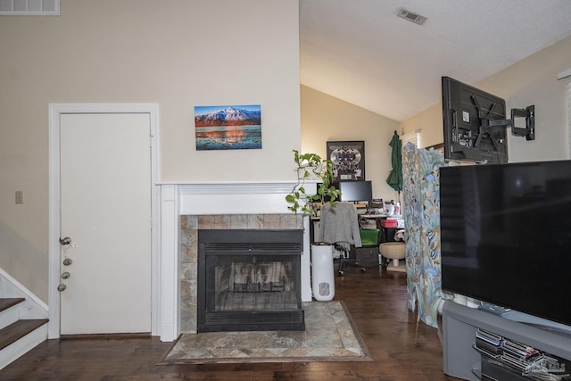 living room featuring dark hardwood / wood-style flooring, a tiled fireplace, and vaulted ceiling