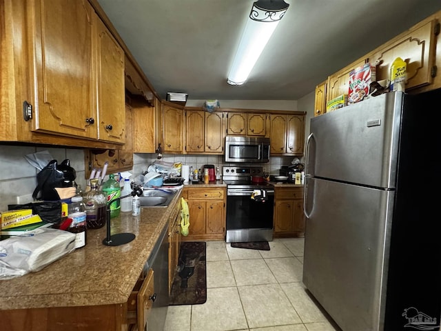 kitchen with backsplash, appliances with stainless steel finishes, sink, and light tile patterned floors