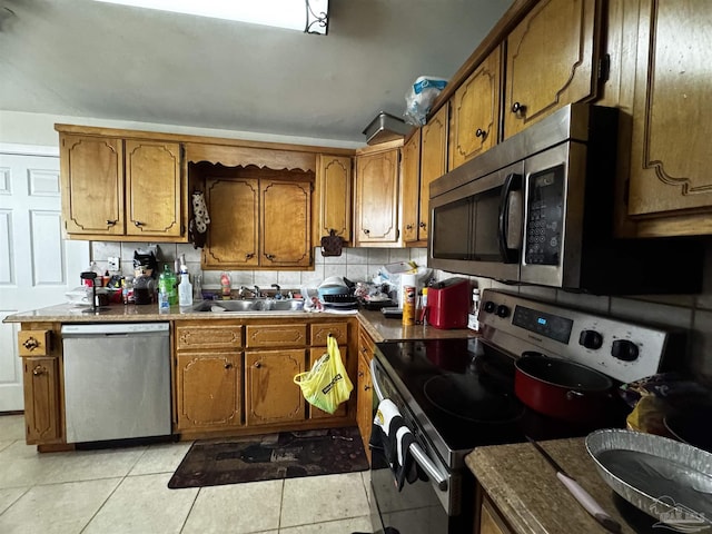 kitchen with stainless steel appliances, sink, light tile patterned floors, and backsplash