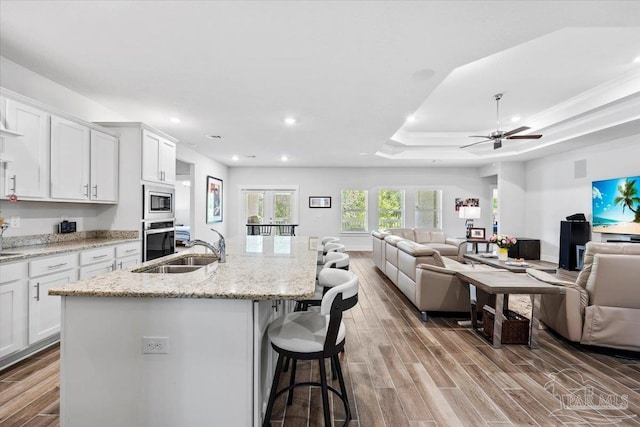 kitchen featuring open floor plan, wood finished floors, a sink, and appliances with stainless steel finishes