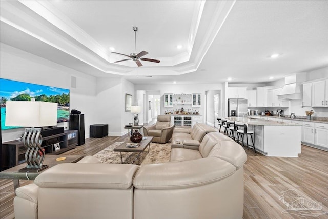 living area featuring ceiling fan, crown molding, a tray ceiling, and recessed lighting