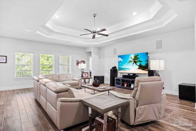 living area featuring recessed lighting, a raised ceiling, a ceiling fan, baseboards, and wood finish floors