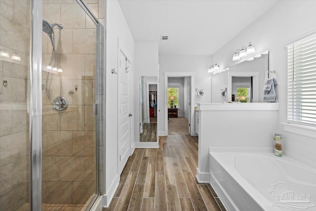 bathroom with a shower stall, a wealth of natural light, a garden tub, and wood finished floors