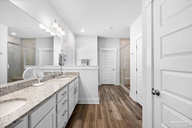 bathroom featuring wood finished floors, a stall shower, and a sink