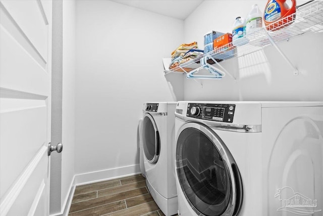 clothes washing area featuring baseboards, wood tiled floor, independent washer and dryer, and laundry area